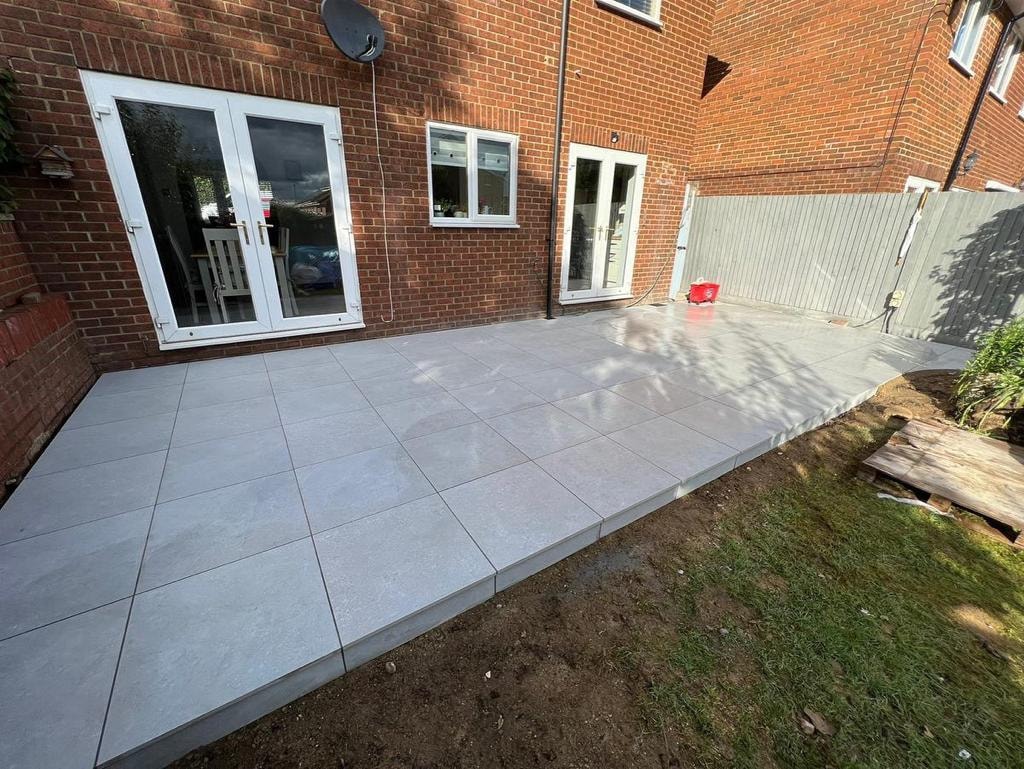 Newly tiled backyard patio beside a brick house
