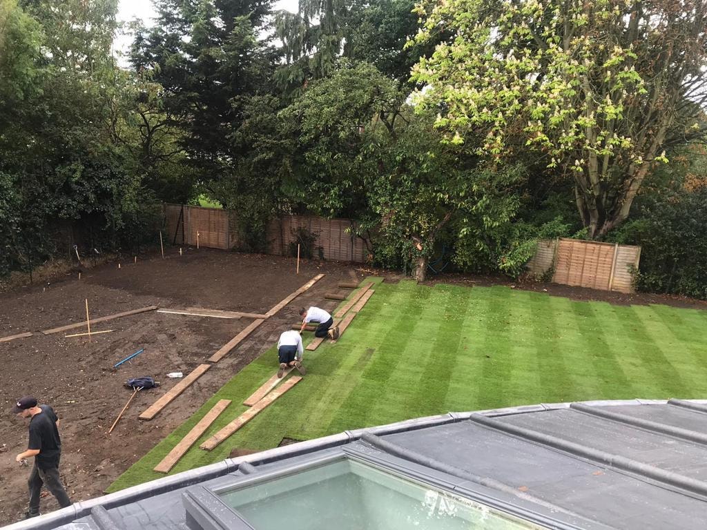 Workers installing artificial grass in a backyard