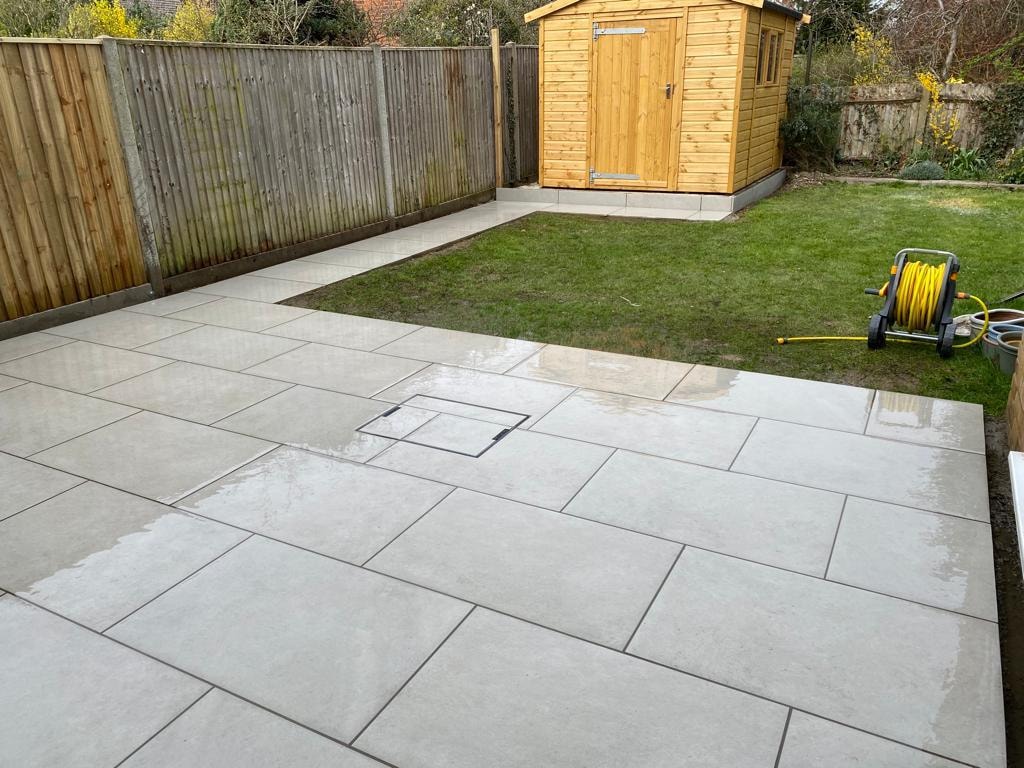 Tiled garden patio with wooden shed and hose reel